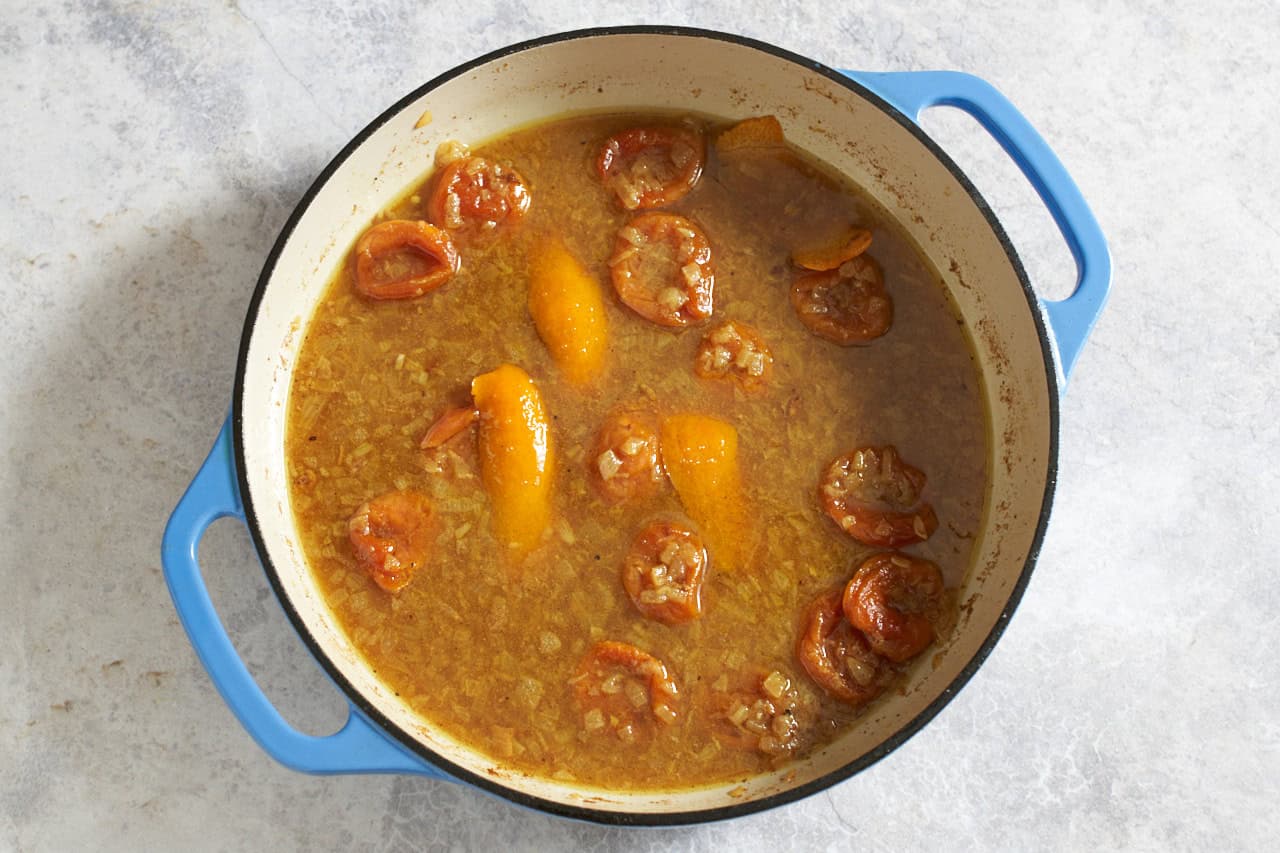 Broth, orange peels, and apricots in a skillet.