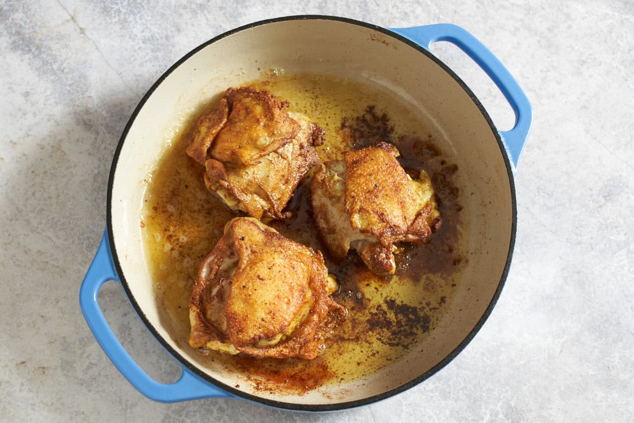 Cooked chicken thighs with crispy skin in a skillet.