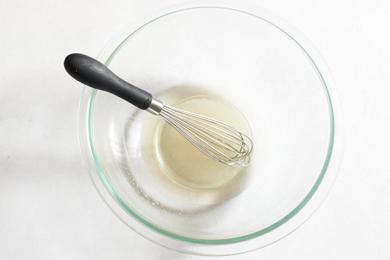 A whisk in a bowl of pickling liquid.
