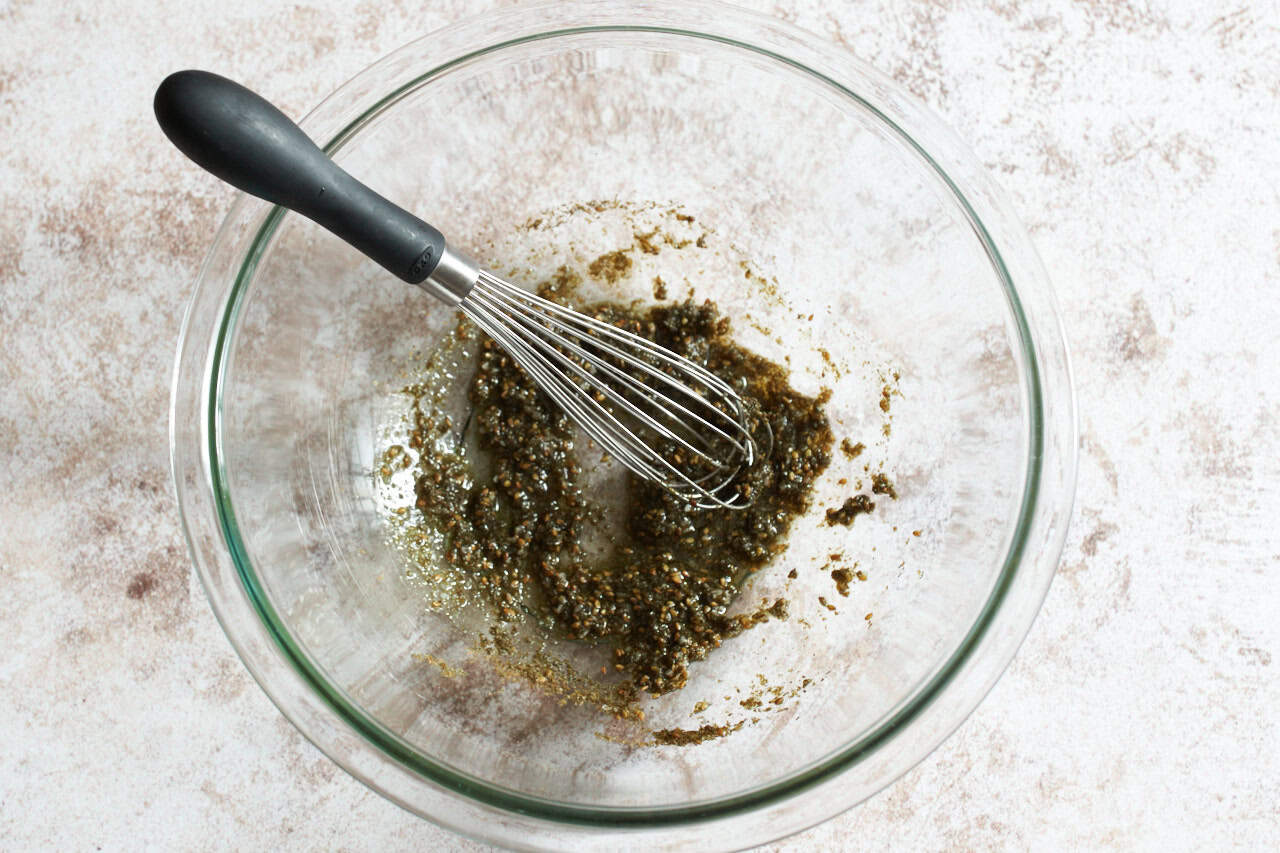 A whisk in a bowl of olive oil and za'atar spice blended together.