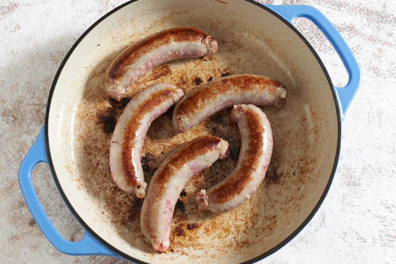 Pan seared bratwursts in a skillet.
