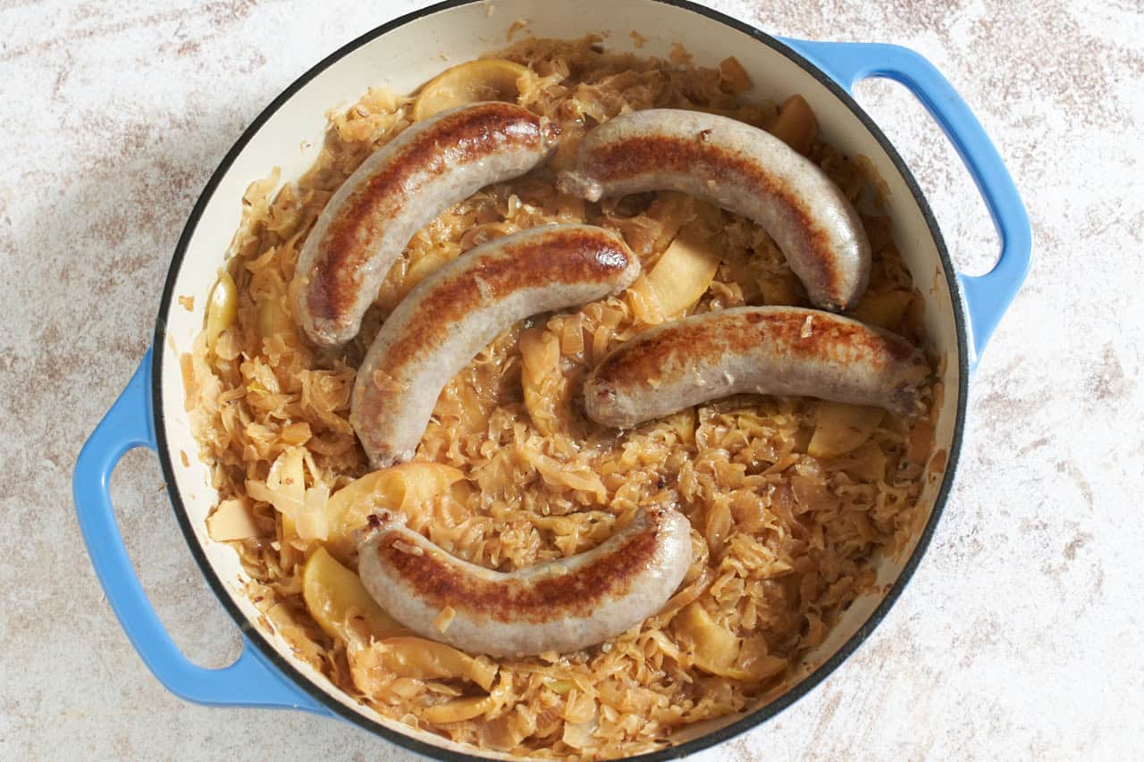 Bratwurst, sauerkraut, apples and onion in a skillet.